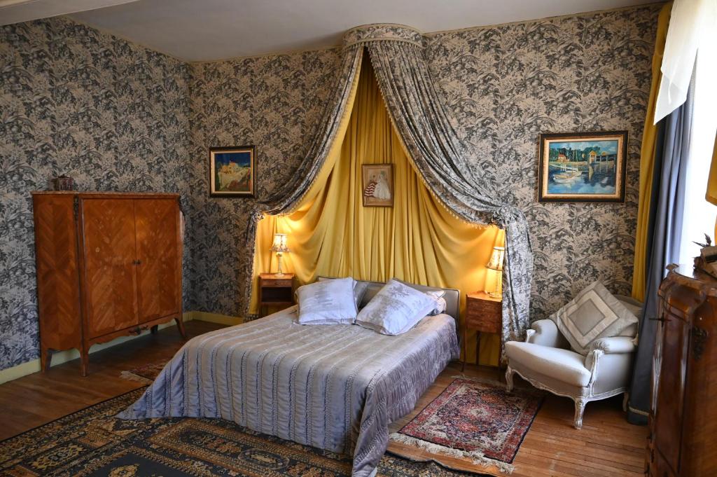 a bedroom with a bed and a chair at Location meublé de tourisme La Rose des Fables in Château-Thierry
