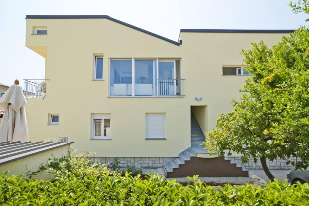 ein gelbes Haus mit Treppe davor in der Unterkunft Apartments Neno in Umag