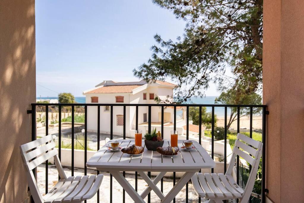 een witte tafel met 2 stoelen op een balkon bij Villa vista mare ~Villa Dafne~ in Noto Marina