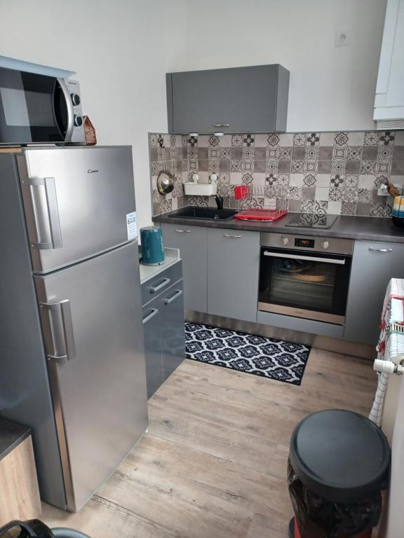 una cucina con frigorifero in acciaio inossidabile e piano cottura di Chez Arthur et Cie a Luxeuil-les-Bains