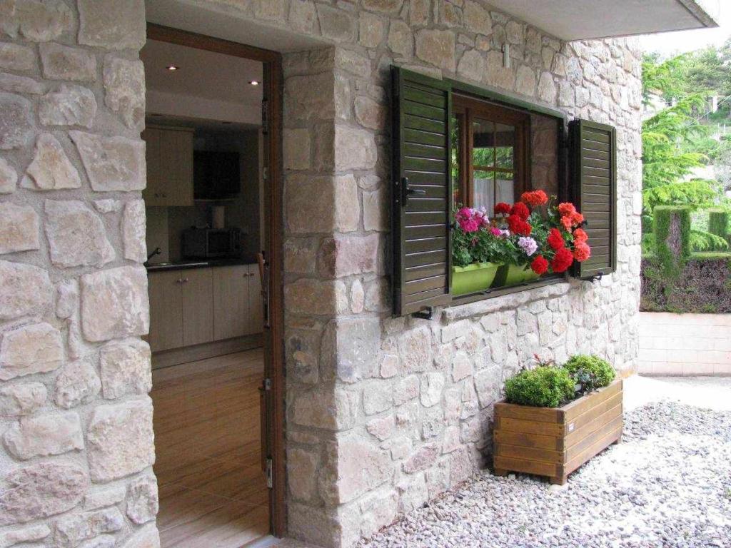 Una pared de piedra con una ventana con flores. en AlpensHolidays Les Pallissses, en Alpens