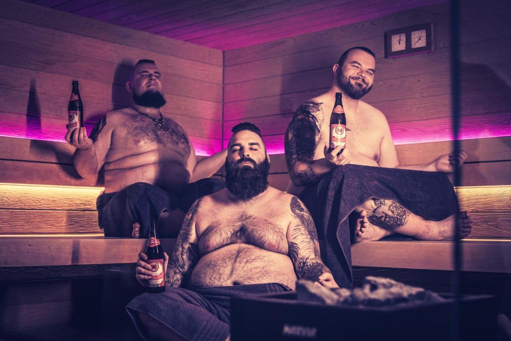 a group of men in a sauna holding bottles of beer at Rock&Chill Hotel Falter in Drachselsried