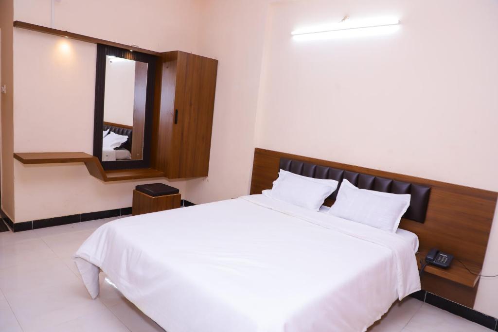 um quarto com uma cama branca e um espelho em Hotel Brahmand em Jejūri