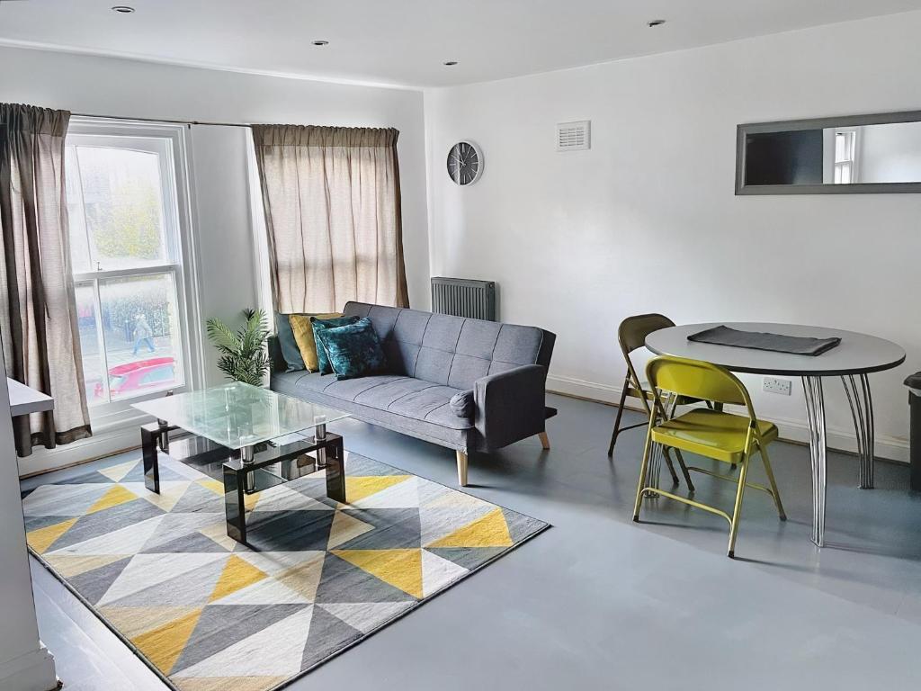 uma sala de estar com um sofá e uma mesa em Lovely 2-bedroom serviced apartment Greater London em Londres