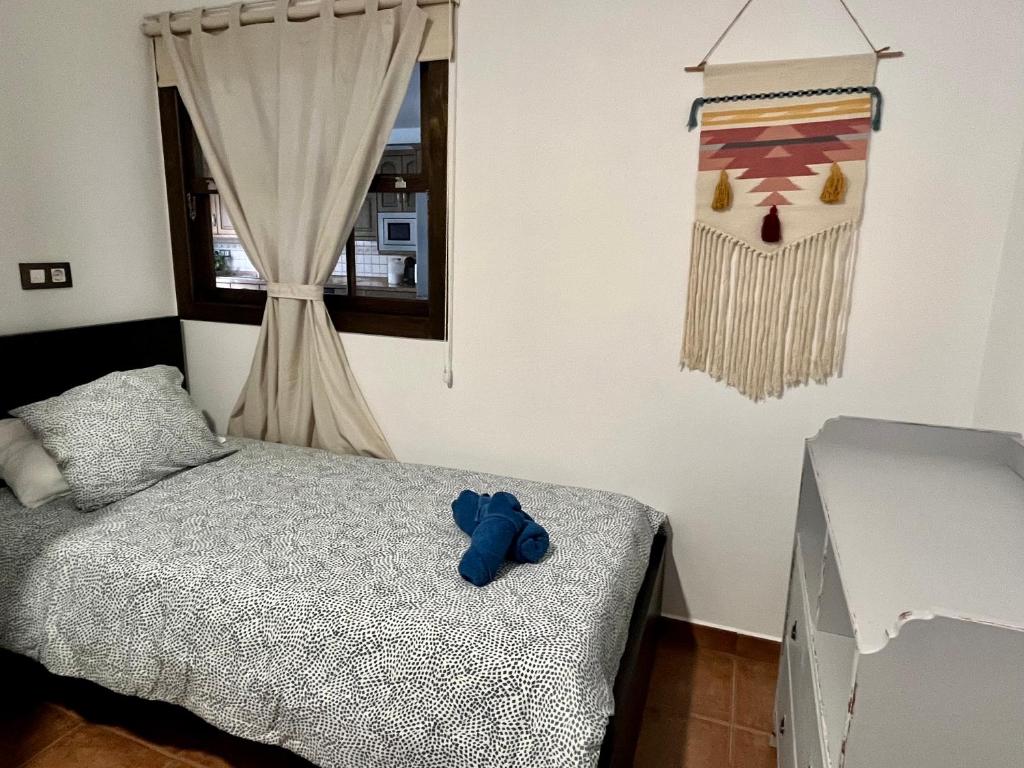 un orsacchiotto blu seduto su un letto in una camera da letto di Casa Canleyy a Los Llanos de Aridane