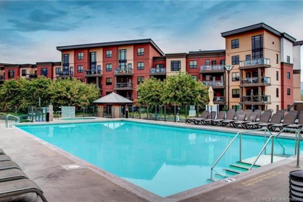 a swimming pool with chairs in front of a building at Upper Floor w Courtyard View 550 in Kelowna