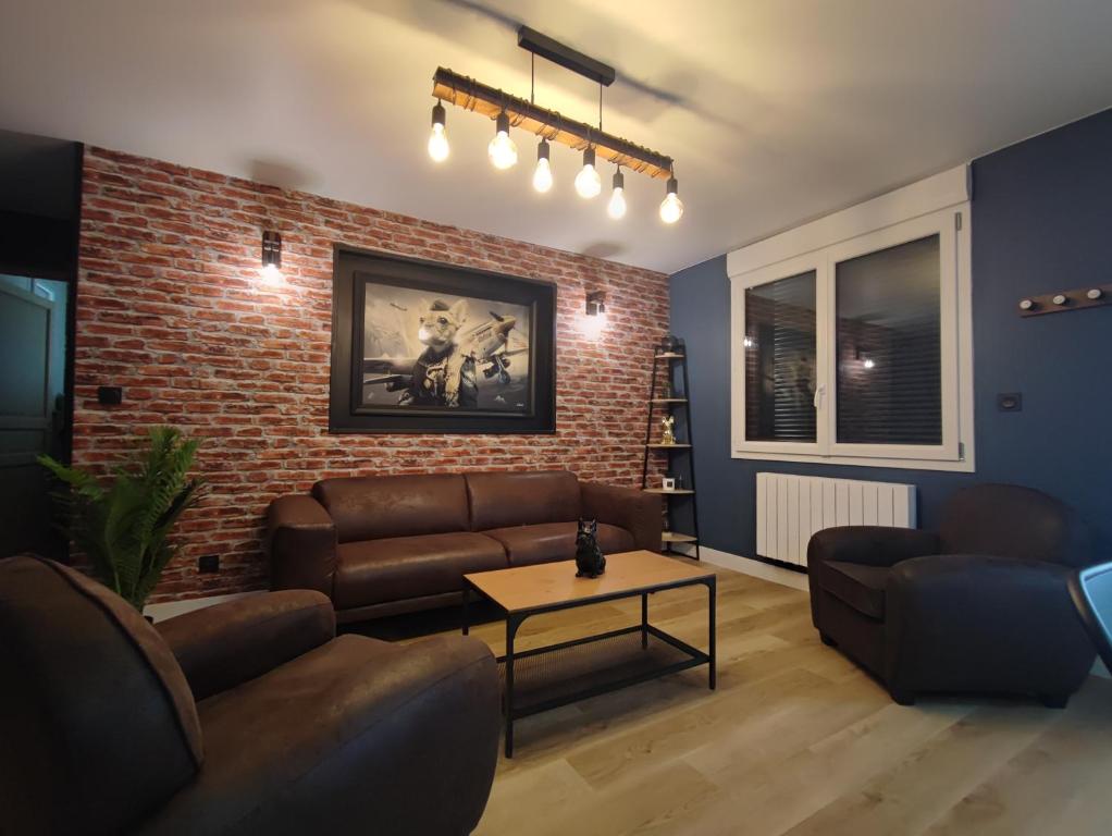 - un salon avec un canapé et un mur en briques dans l&#39;établissement Le Gîte de Daisy, à Saint-Côme-du-Mont