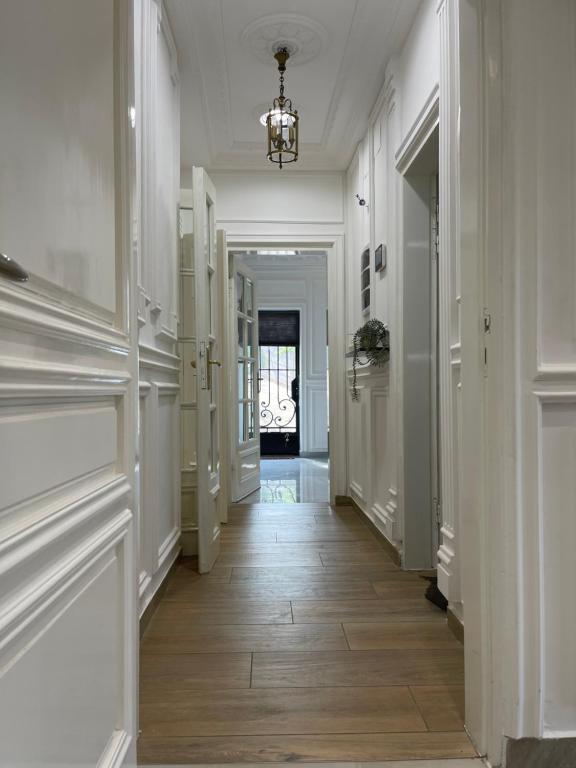 a hallway with white walls and wood floors and a chandelier at EVE HOME in Yaoundé