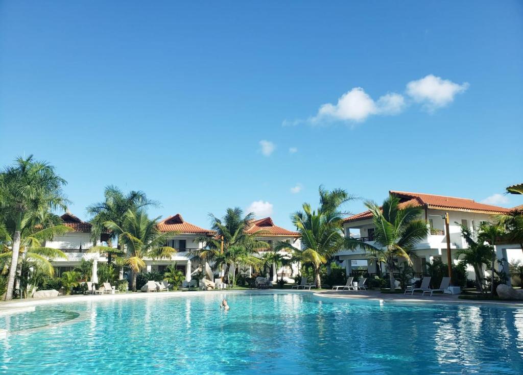 a pool at a resort with palm trees and houses at Residencial Paraiso Bayahibe in Bayahibe