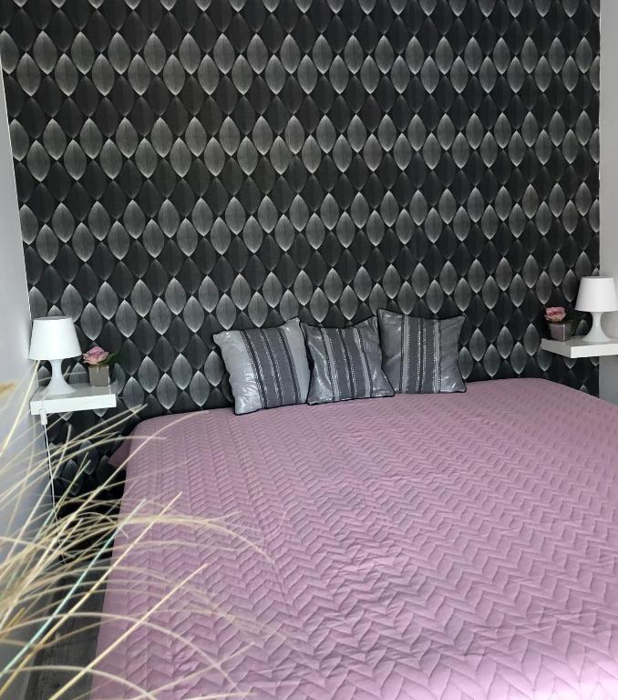 una camera con un letto viola e una grande testiera del letto di Agnes Apartman a Latschach