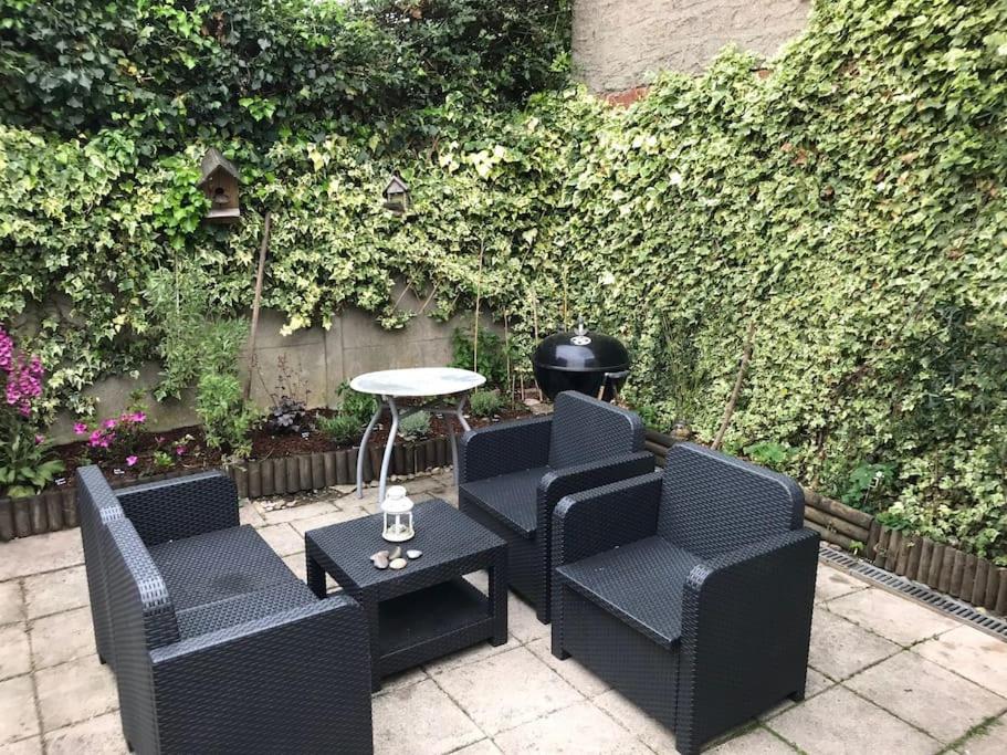 une terrasse avec des chaises, une table et une haie dans l'établissement Chez Lulu, à Montreuil