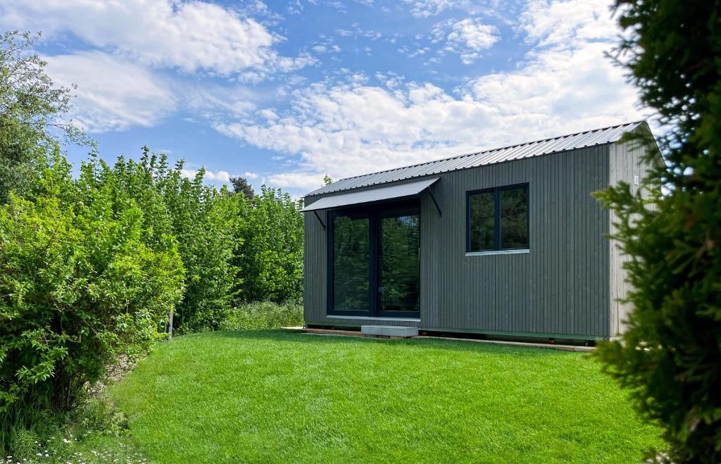 a small house in a yard with a green lawn at Tiny House - Camping Wagenhausen in Wagenhausen