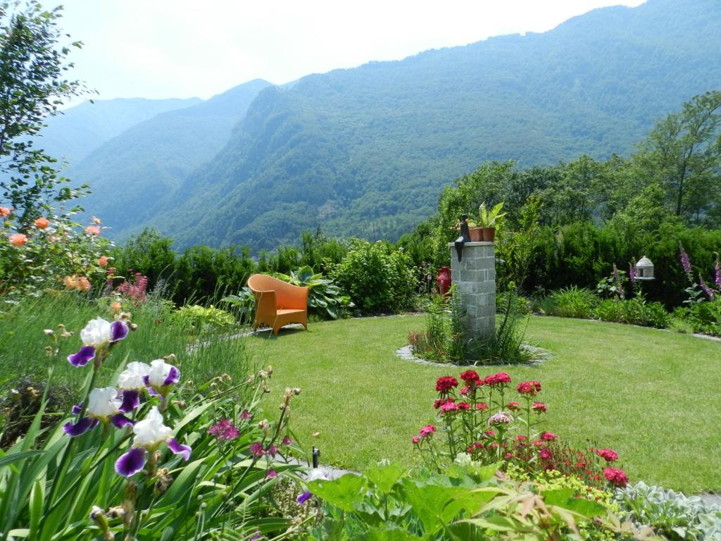 a garden with a chair and mountains in the background at CASA ALLA CASCATA House by the Waterfall and Garden of Senses in Maggia