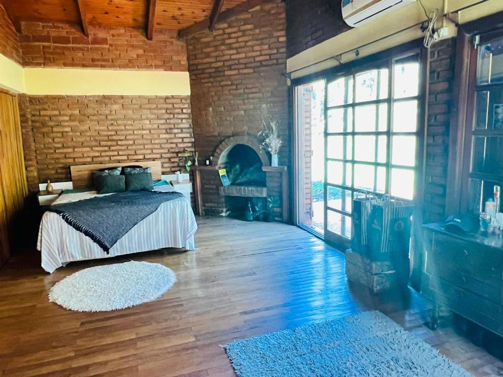 um quarto com uma cama e uma parede de tijolos em Casa de Campo La Olivia em Eldorado
