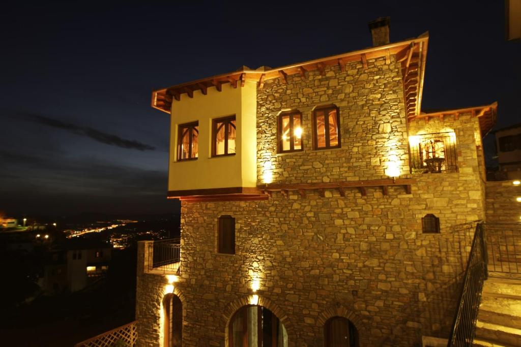 a building with lights in the windows at night at Archontiko Polyzos in Portaria