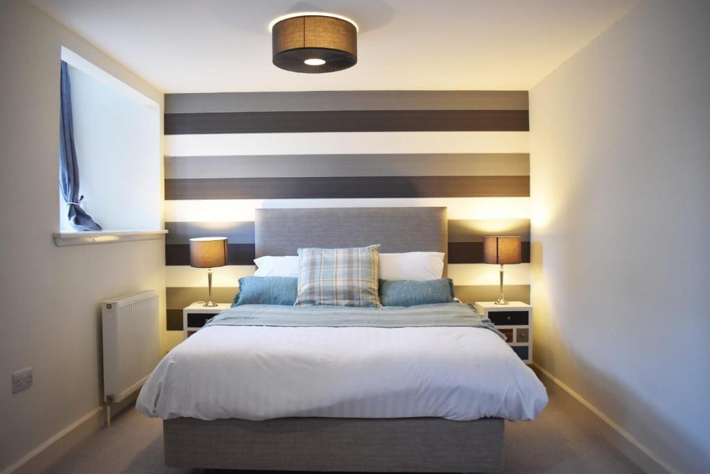 a bedroom with a bed with a striped accent wall at Monastery apartment with Loch Ness view in Fort Augustus