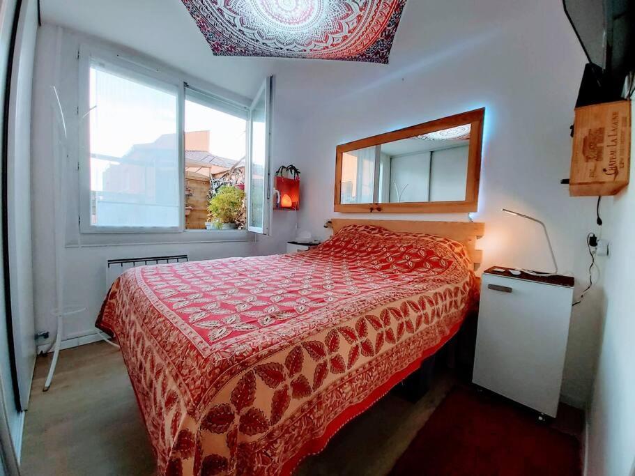- une chambre avec un lit doté d'un couvre-lit rouge et d'une fenêtre dans l'établissement T2 cosy à la plage, terrasse vue sur mer et parking privatif, à Narbonne