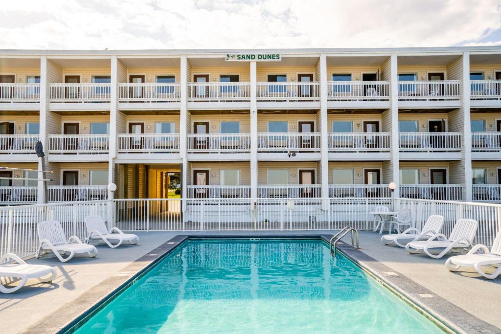 a pool in front of a hotel with chairs and a building at The Sand Dunes in Kure Beach