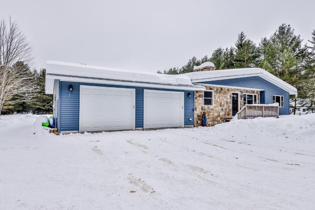uma casa azul com duas portas de garagem na neve em Echo Lodge em Mercer