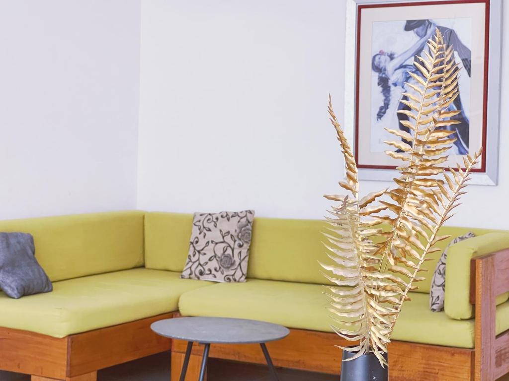 ein gelbes Sofa im Wohnzimmer mit Pflanze in der Unterkunft Appartement 3 chambres Mamelles in Dakar