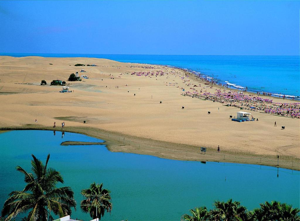 una playa con un montón de gente en ella en Oasis Playa Maspalomas en Maspalomas