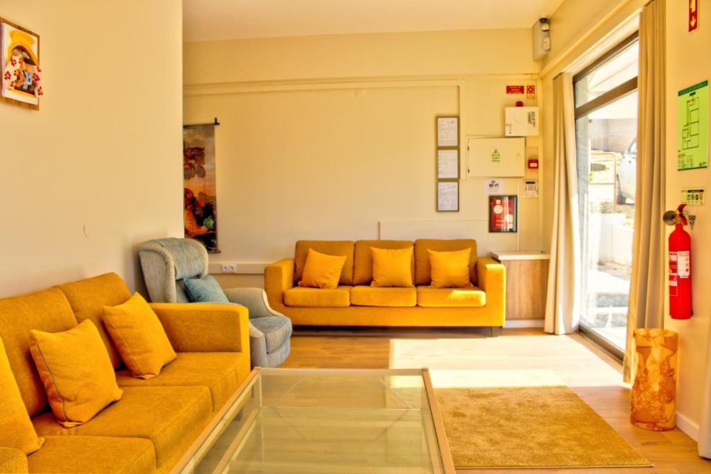 un soggiorno con 2 divani gialli e una finestra di Blue Ocean Guesthouse ad Atouguia da Baleia