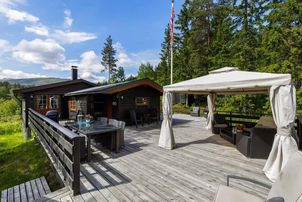 een houten terras met een tent en een hut bij Bromlebu in Notodden