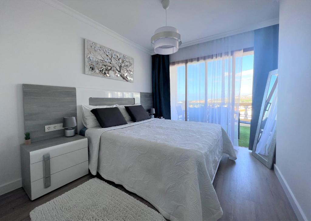 een witte slaapkamer met een bed en een groot raam bij PaulMarie Family Apartment Ocean&Mountain View in Adeje