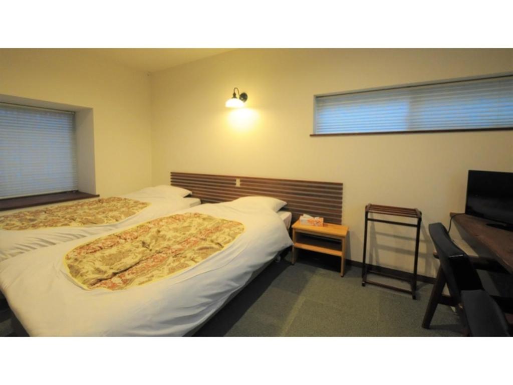 a bedroom with two beds and a desk and a television at Yoro Onsen Honkan - Vacation STAY 09622v in Onomichi
