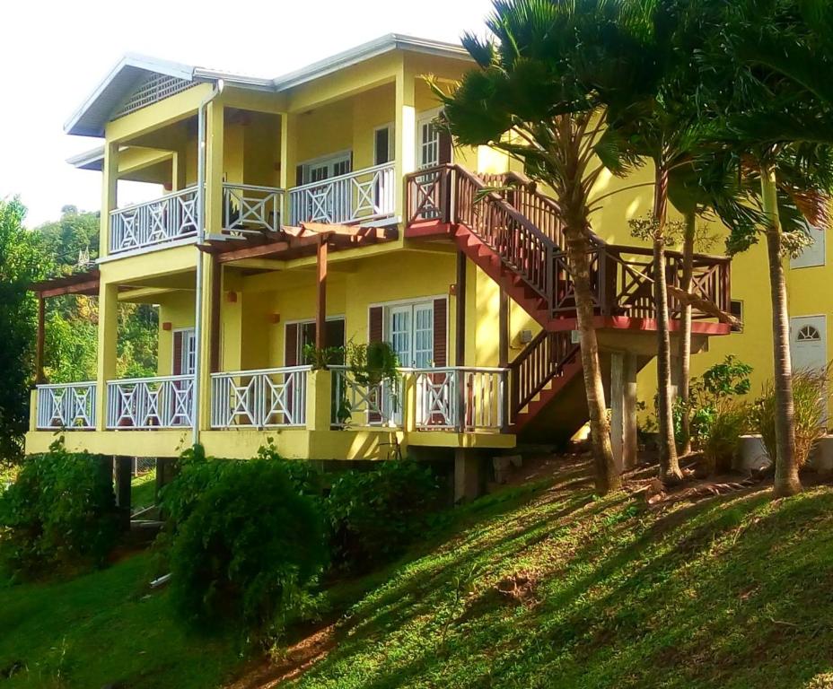 a yellow house with a balcony and palm trees at Seascape Villa 3BR with Stunning Caribbean Sea View in Castries