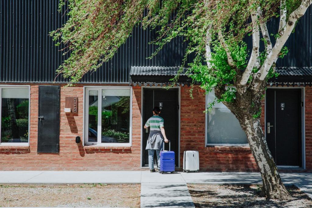 un homme sortant d'un bâtiment avec une valise dans l'établissement Hol Gok Patagonia, à Esquel