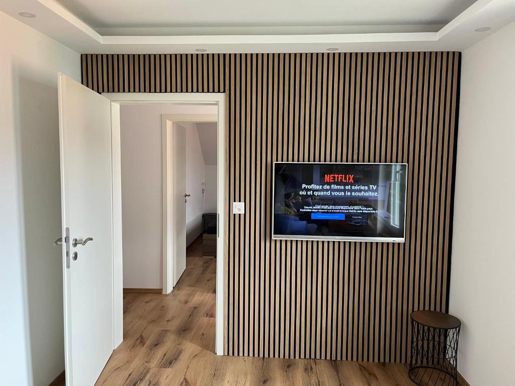 a living room with a television on a striped wall at Studio cosy au centre de Couvet in Couvet