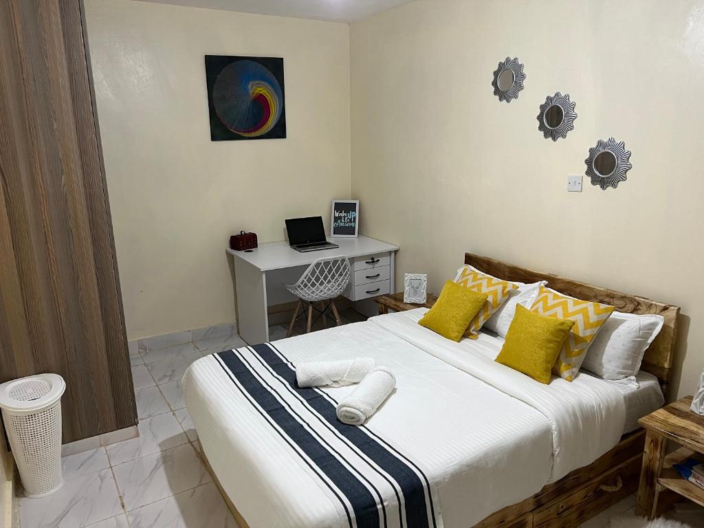 Un dormitorio con una cama grande con almohadas amarillas y blancas en Ruby Modern Homes-2br-Nyeri, King'ong'o-Knights, en Nyeri