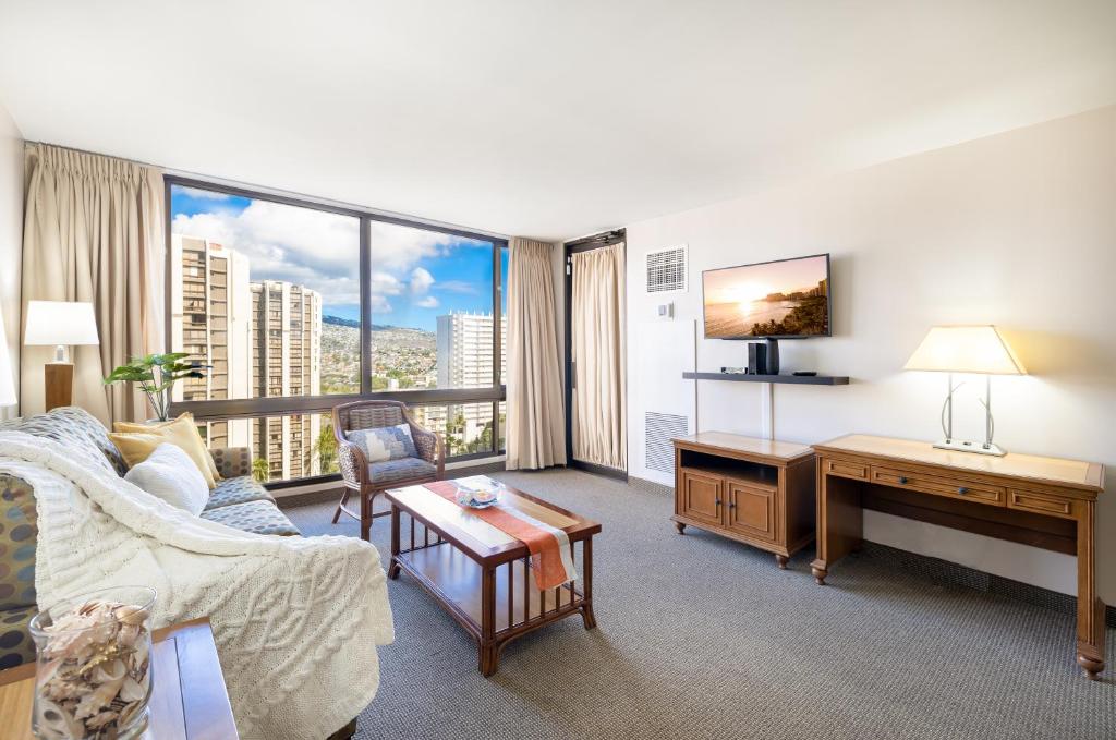 a living room with a couch and a desk and a large window at Beautiful Mountain Views Condo, Parking is free! in Honolulu