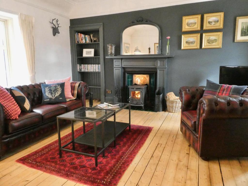 a living room with leather furniture and a fireplace at Caman House Apt 2 - by Where Stags Roar in Newtonmore