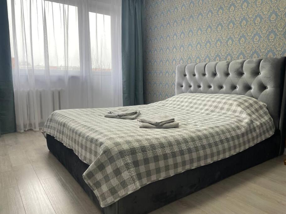 a bed with a checkered blanket and two shoes on it at Klaipeda Center Apartment in Klaipėda