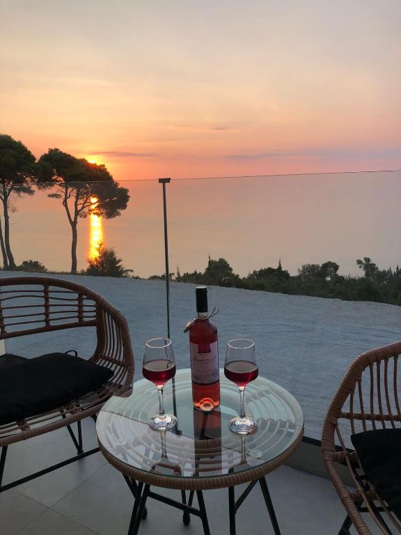 two glasses of wine sitting on a table with the sunset at Selene houses in Athanion