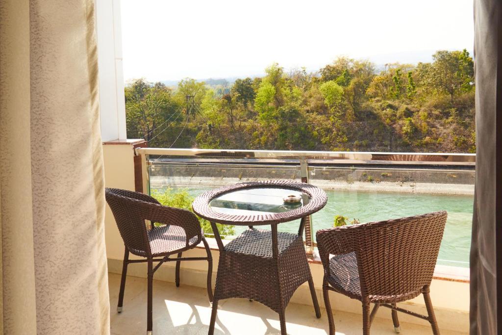 balcón con mesa, sillas y vistas a la piscina en Rajaji Delight, Rajaji National Park, Rishikesh en Rishīkesh