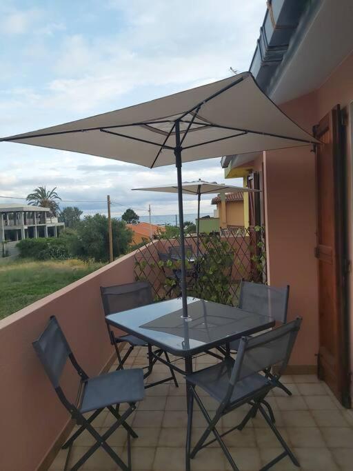 una mesa y sillas en un balcón con sombrilla en Casa rossa, en Solanas