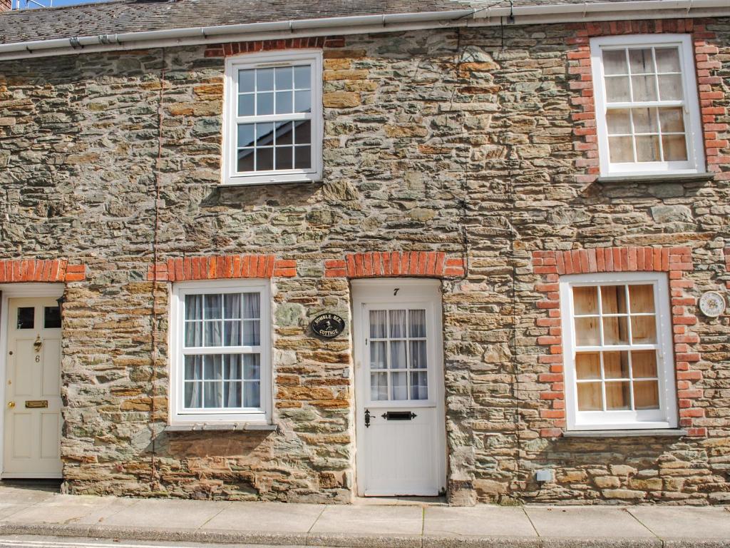 a stone building with two white doors and windows at Bumblebee Cottage in Salcombe