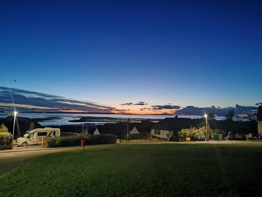 a view of a field with a sunset in the background at Owen's Garden Hideaway in Conwy