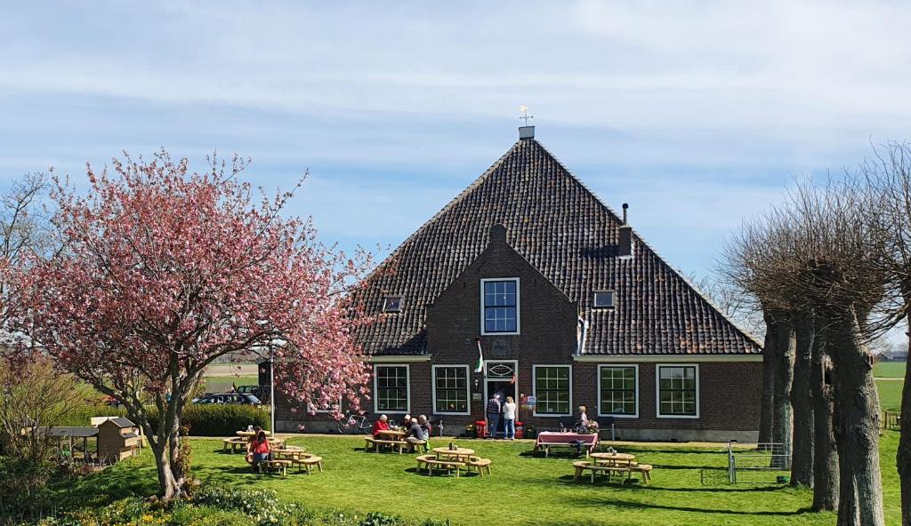 una casa grande con gente parada frente a ella en Vakantieboerderij Huize Nuis en Noordbeemster
