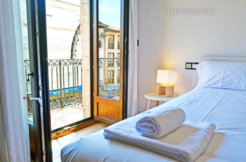 een slaapkamer met een bed en een balkon met uitzicht bij Apartamento Llerandi 2B - Totalmente reformado y con balcón al corazón de San Vicente de la Barquera in San Vicente de la Barquera