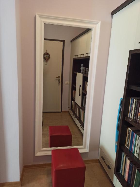 a mirror in a hallway with two red stools at Home Sweet Rental in Tirana