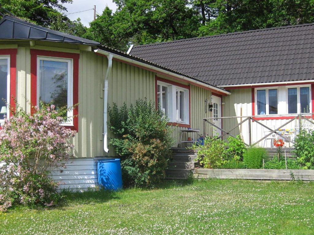 a green house with a red door and a yard at Three-Bedroom Holiday home in Skå in Ekerö