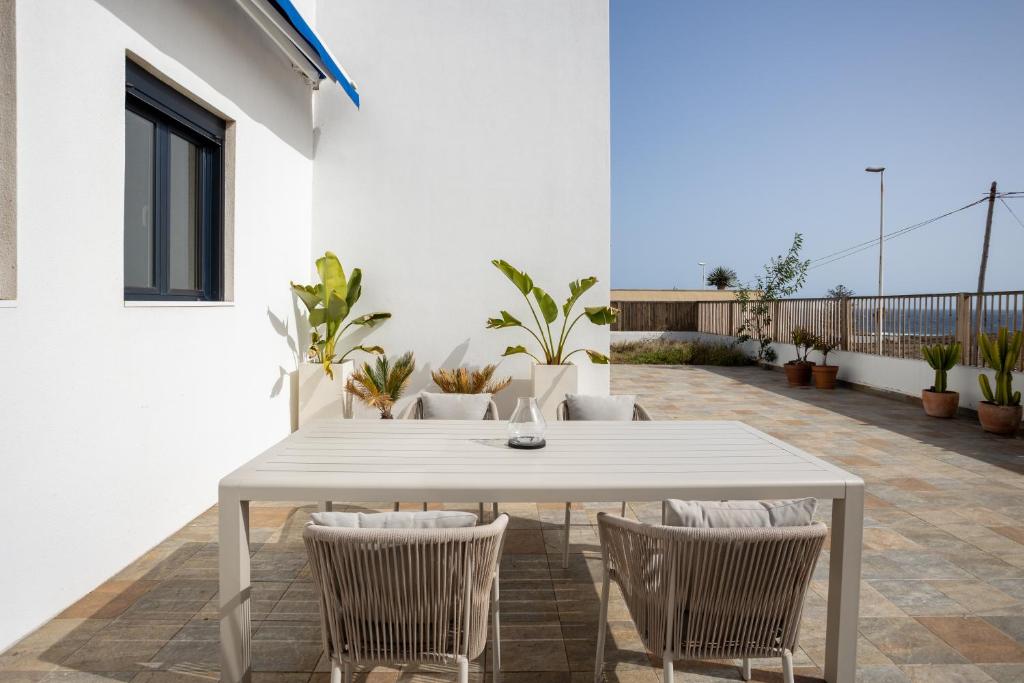 Villa Arizona - 3-bedroom house by the sea في إل ميدانو: طاولة بيضاء وكراسي على الفناء