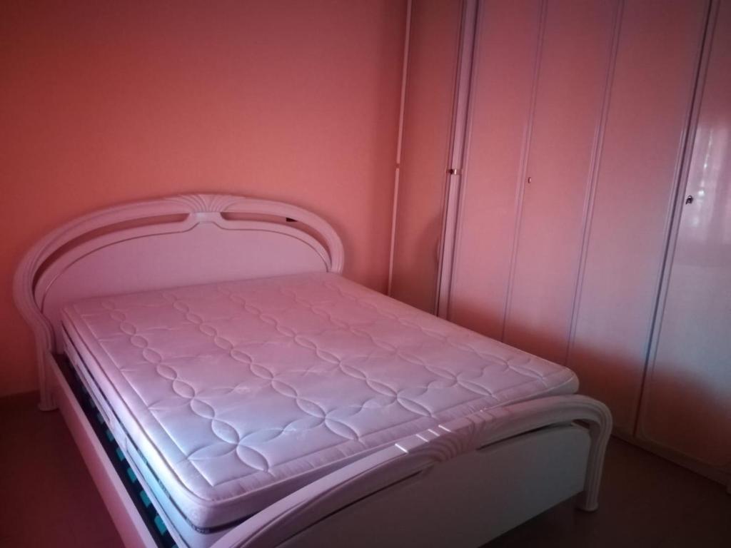 - un petit lit dans une chambre aux murs roses dans l'établissement Appartamento mare, à Siderno Marina