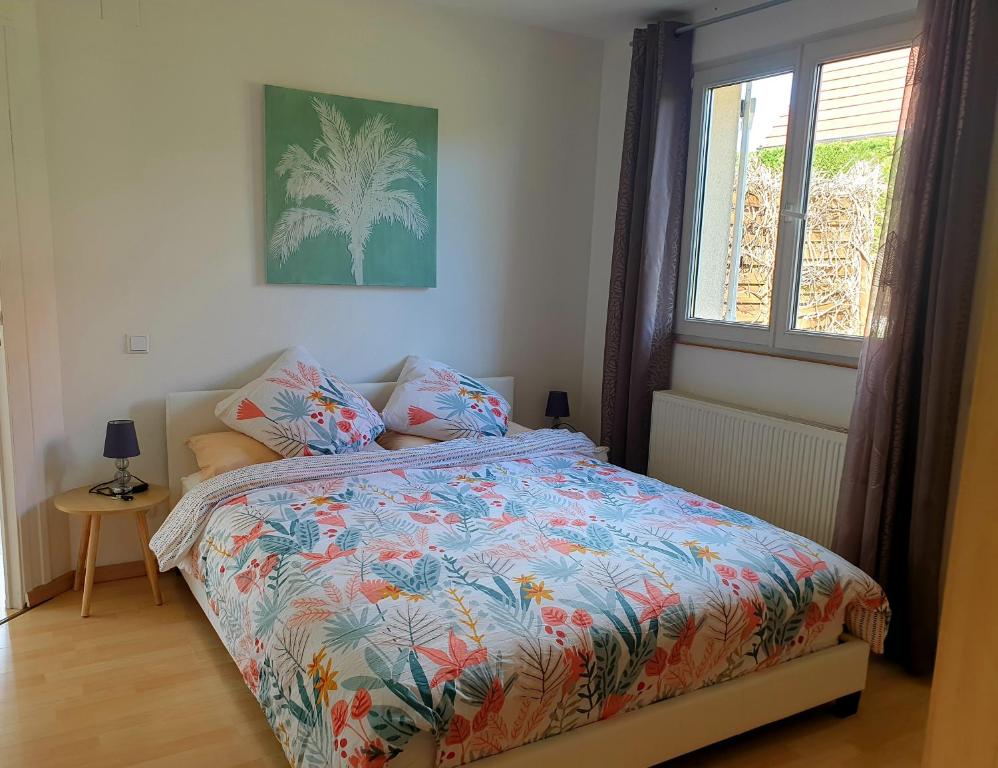 a bedroom with a bed with a colorful comforter and a window at Appartement proche d'Europa park/Marchés de Noël in Rhinau