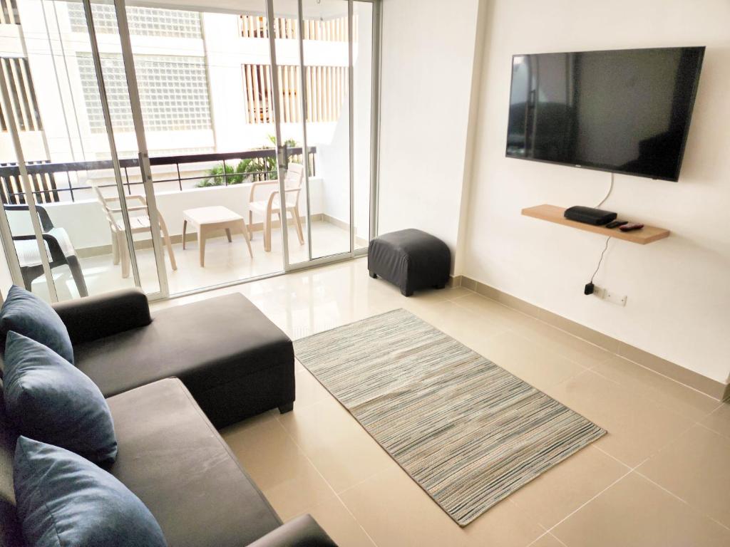 sala de estar con sofá y TV de pantalla plana en Apartamento 3 habitaciones Palanoa Rodadero - By Bedviajes, en Santa Marta