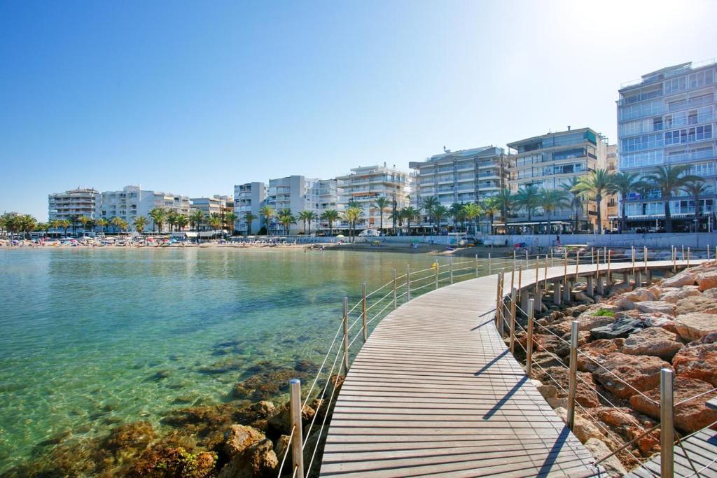 una passerella in legno sull'acqua vicino a una spiaggia di Apartamento Salou Playa Jaime I a Salou